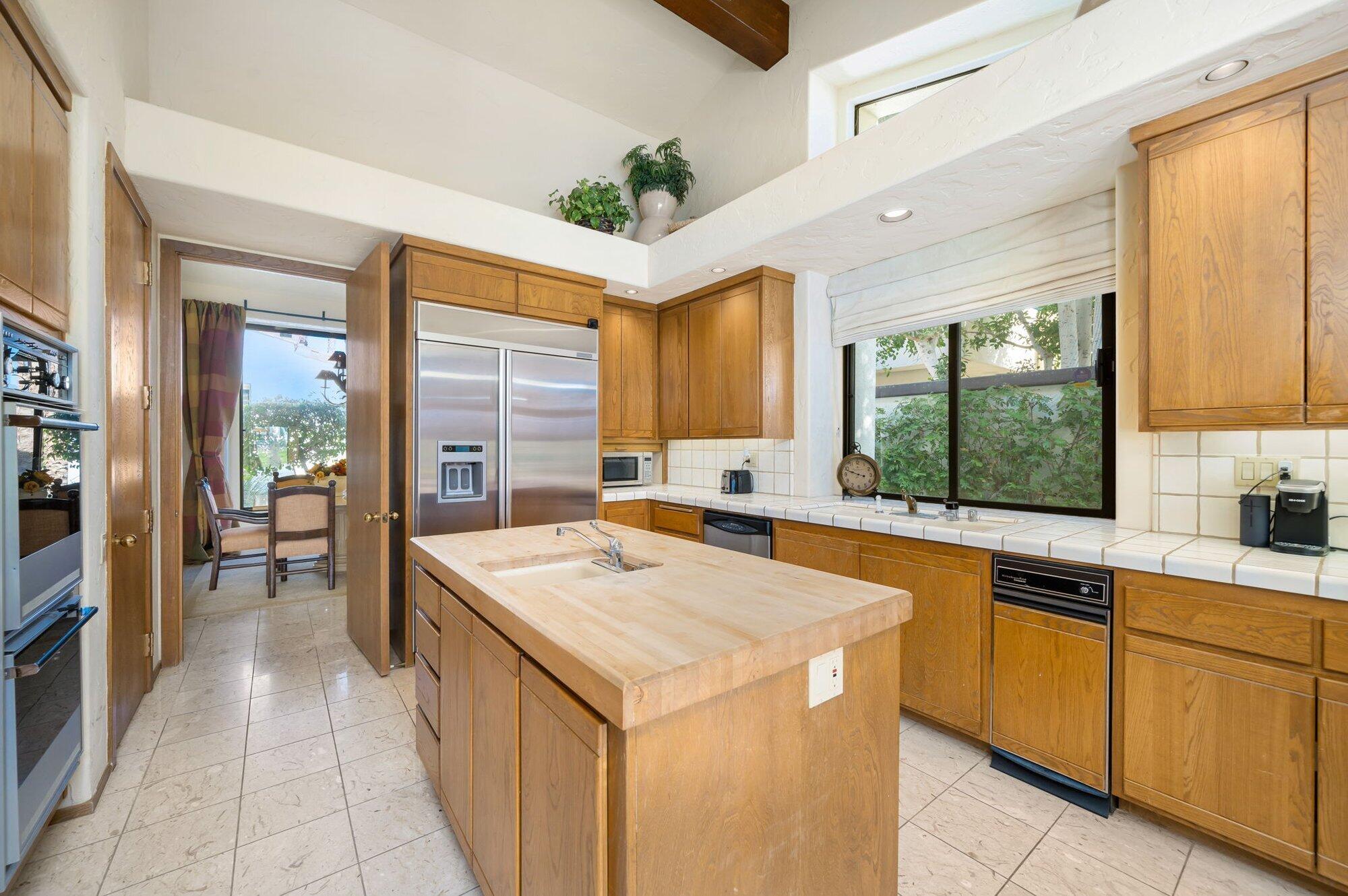 55880 Pinehurst La Quinta, CA 92253 - Photo 29 of 54 a kitchen with a stove a sink a refrigerator and wooden cabinets