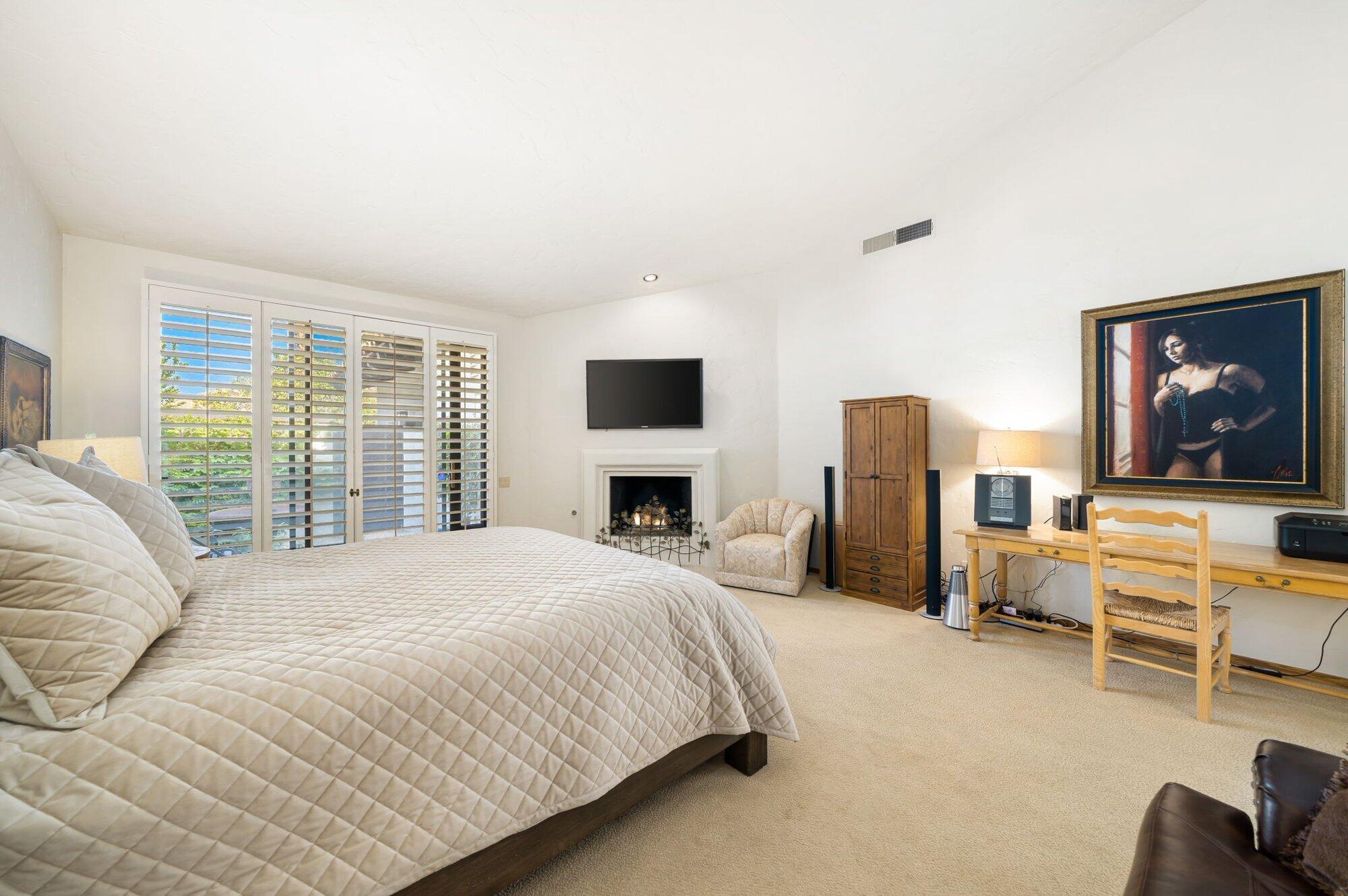 55880 Pinehurst La Quinta, CA 92253 - Photo 39 of 54 a bedroom with a large bed a flat tv screen and a fireplace