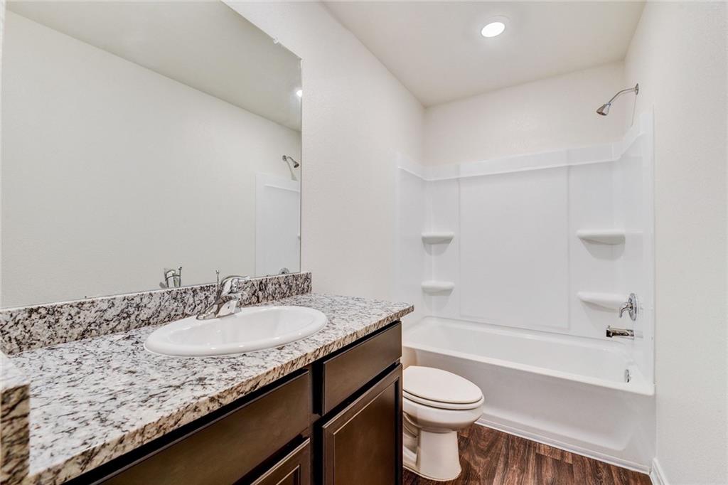 14008 Prospector Way Elgin, TX 78621 - Photo 7 of 7 a bathroom with a granite countertop sink toilet and shower