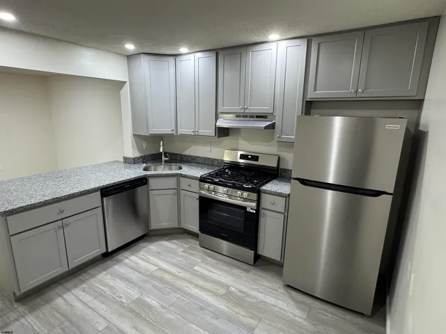 a kitchen with stainless steel appliances granite countertop a refrigerator a sink a stove and cabinets