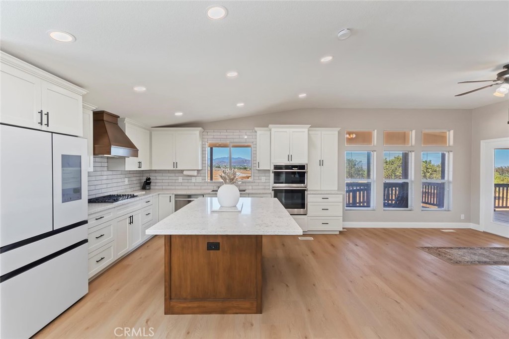 19310 Ann Way Perris, CA 92570 - Photo 12 of 75 a large kitchen with kitchen island a stove a sink a refrigerator and white cabinets with wooden floor