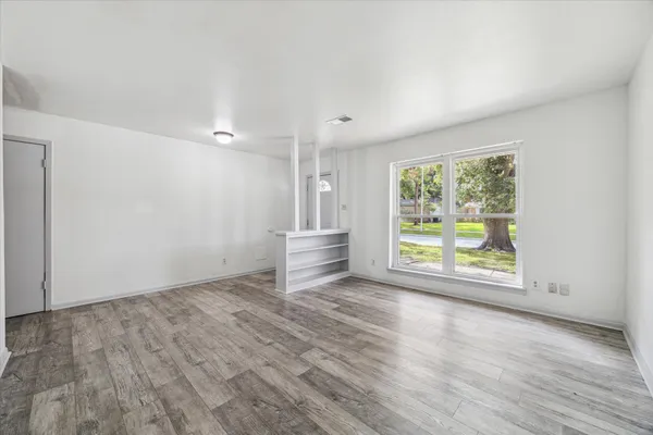 an empty room with wooden floor and windows