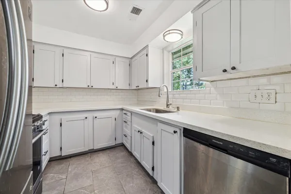 a kitchen with granite countertop white cabinets white appliances and a sink