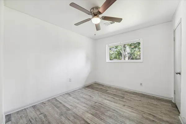 an empty room with wooden floor and ceiling fan