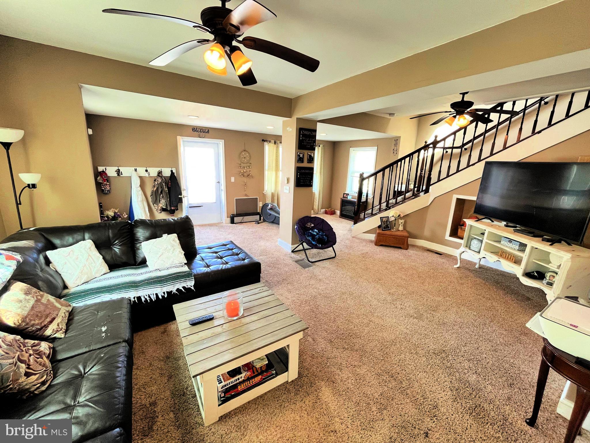 a living room with furniture flat screen tv and a ceiling fan