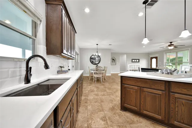 a kitchen with kitchen island granite countertop a sink cabinets and stainless steel appliances