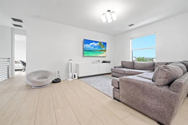 a living room with furniture a flat screen tv and a window