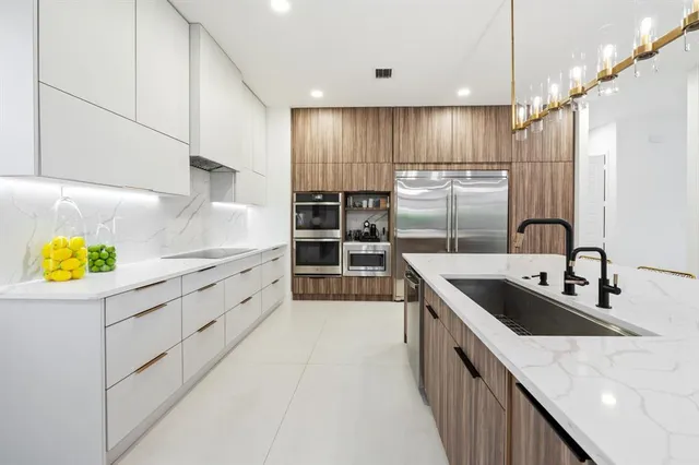 a kitchen with kitchen island granite countertop a sink a counter space appliances and cabinets