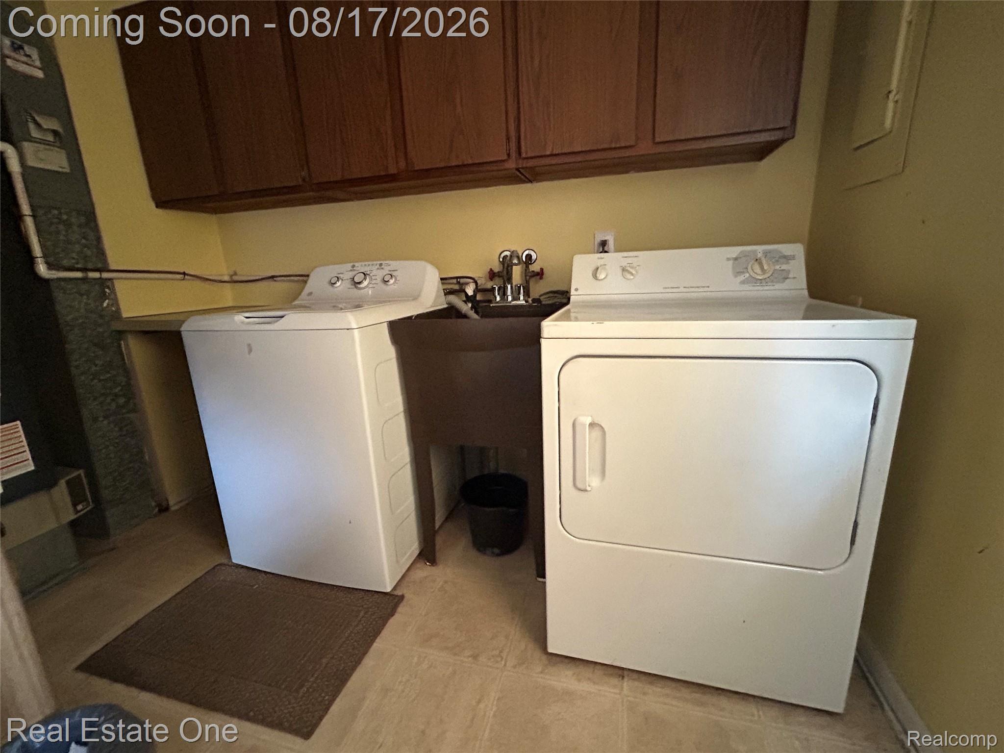 22967 Northline Road Taylor, MI 48180 - Photo 19 of 22 Dedicated utility space featuring overhead wood-finish cabinetry, a utility sink, and a tiled floor