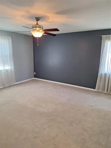 a view of an empty room with a chandelier fan
