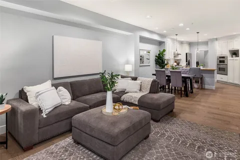 a living room with furniture potted plant and kitchen view