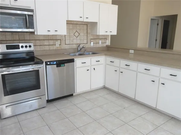 a kitchen with granite countertop white cabinets stainless steel appliances and a sink