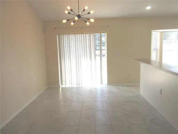 en empty room with windows and chandelier fan