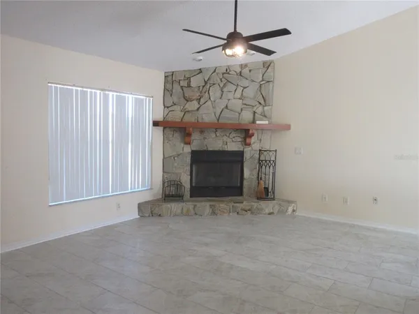 an empty room with a fireplace and chandelier fan