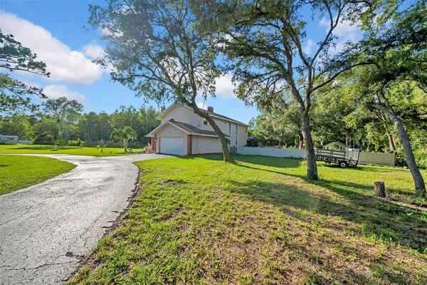 a view of a house with a big yard and large trees
