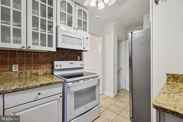 a kitchen with granite countertop white cabinets and stainless steel appliances