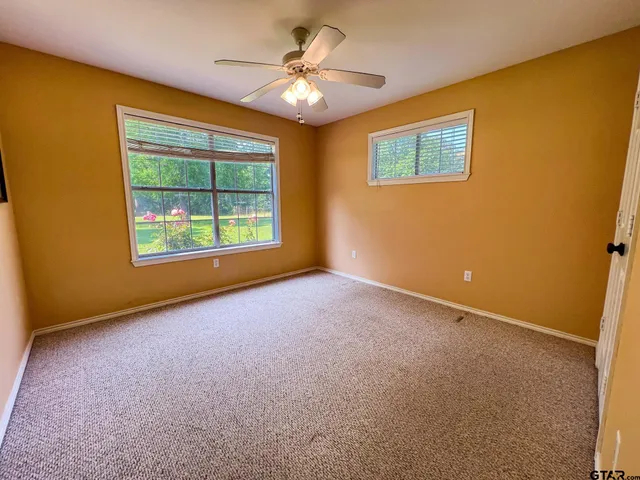 an empty room with windows and ceiling fan