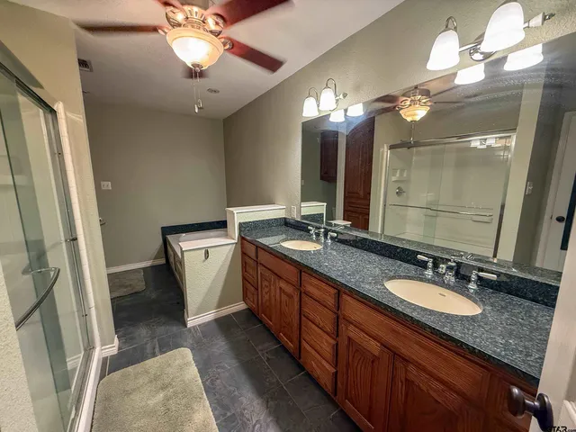 a bathroom with a granite countertop double vanity sink a mirror and a shower