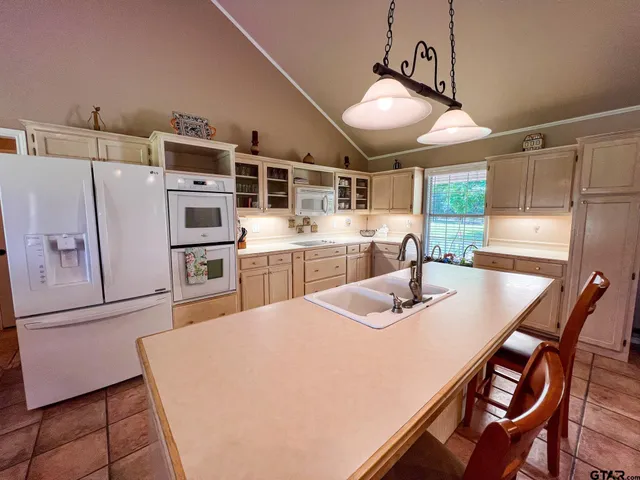 a kitchen with stainless steel appliances granite countertop a refrigerator a sink a stove a dining table and chairs with wooden floor