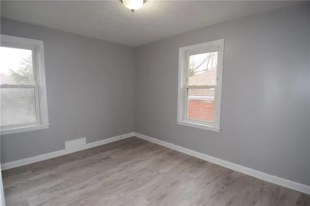 an empty room with wooden closet and windows