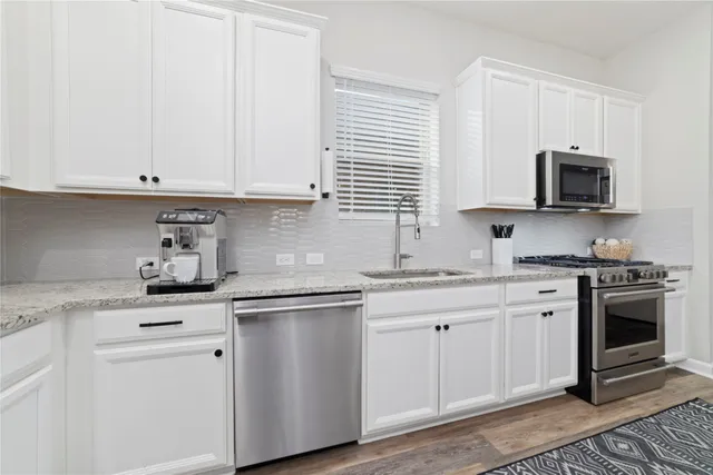 a kitchen with white cabinets and appliances