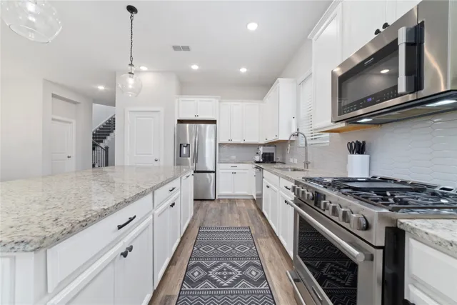 a large kitchen with stainless steel appliances granite countertop a stove a sink and a microwave