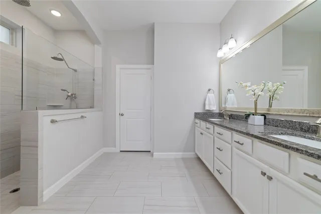 a spacious bathroom with a granite countertop sink a mirror and a shower