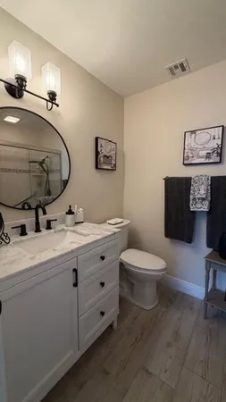 a bathroom with a toilet a double vanity sink and a mirror