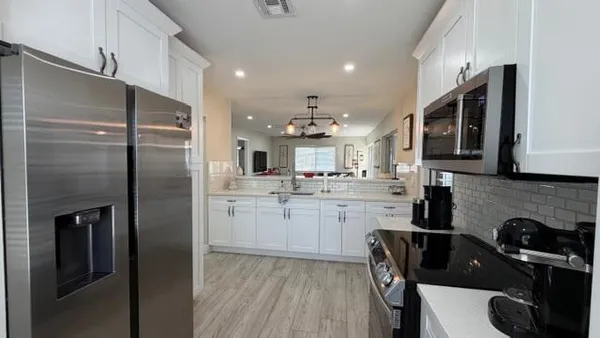 a kitchen with kitchen island stainless steel appliances a sink stove refrigerator and cabinets