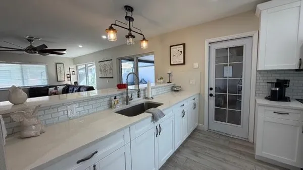 a large white kitchen with a large window a sink and cabinets