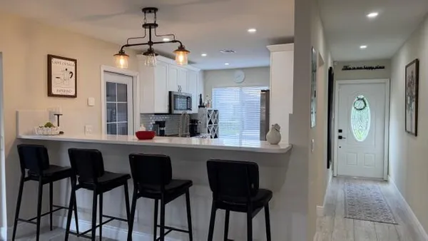 a kitchen with stainless steel appliances kitchen island granite countertop a dining table chairs and sink