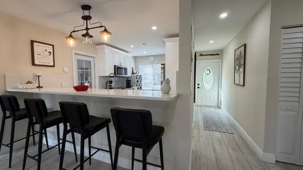 a kitchen with stainless steel appliances kitchen island granite countertop a dining table chairs and a refrigerator