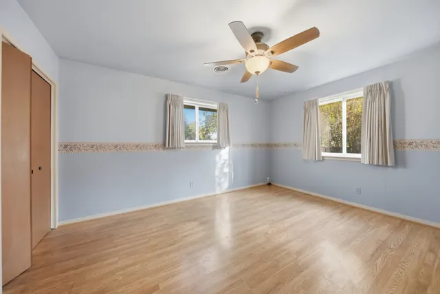 a view of an empty room with window and wooden floor