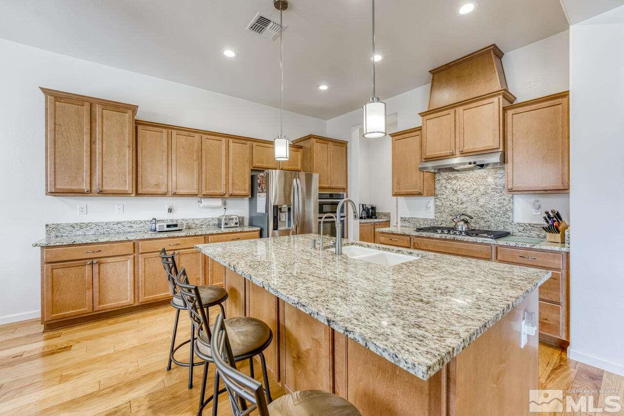 9950 Bernborough Drive Reno, NV 89521 - Photo 6 of 29 a kitchen with kitchen island granite countertop wooden cabinets and a refrigerator