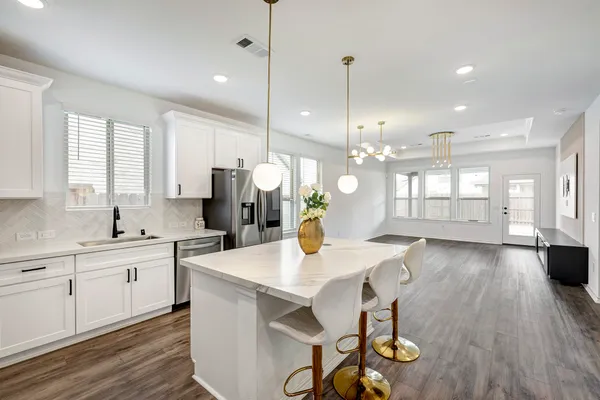 a open kitchen with stainless steel appliances granite countertop a stove a sink dishwasher a dining table and chairs with wooden floor