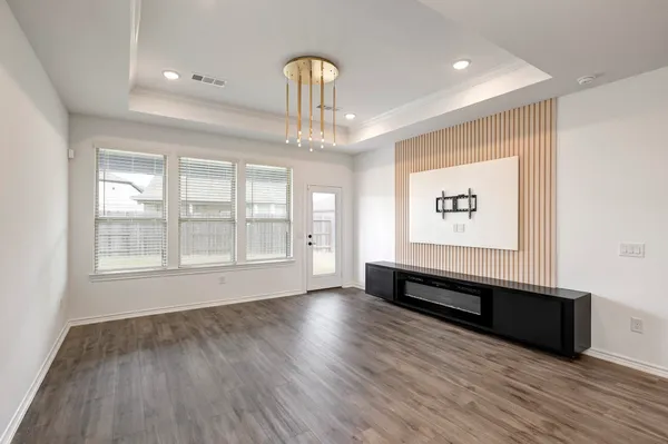a view of a room with wooden floor chandelier and windows