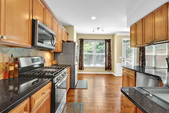 a kitchen with stainless steel appliances granite countertop a stove a sink and a microwave