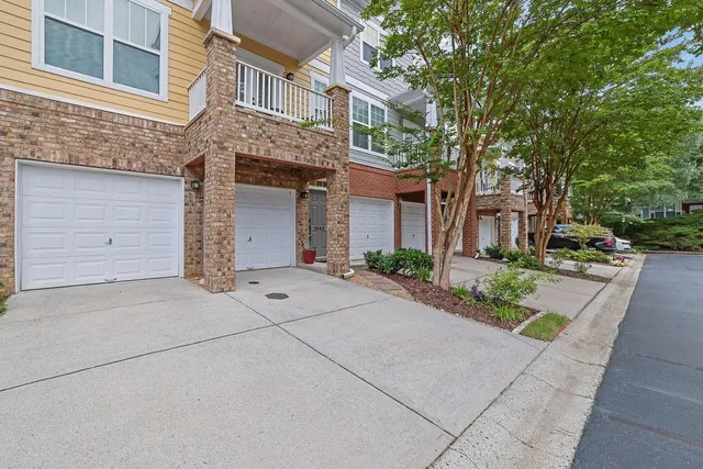 front view of a brick house with a yard and large trees