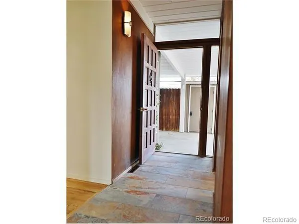 a view of a hallway with wooden floor and a large mirror