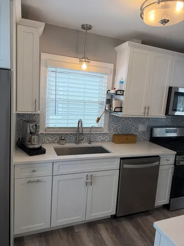 a kitchen with white cabinets and sink