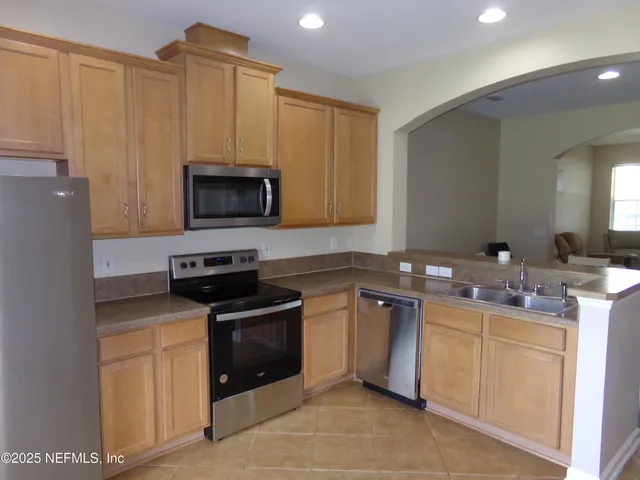 a kitchen with stainless steel appliances a sink a stove a microwave a refrigerator and cabinets