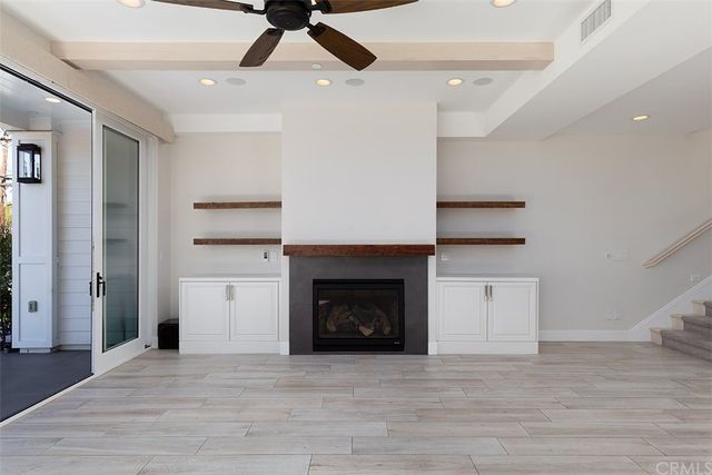 a view of an empty room with wooden floor and a fireplace