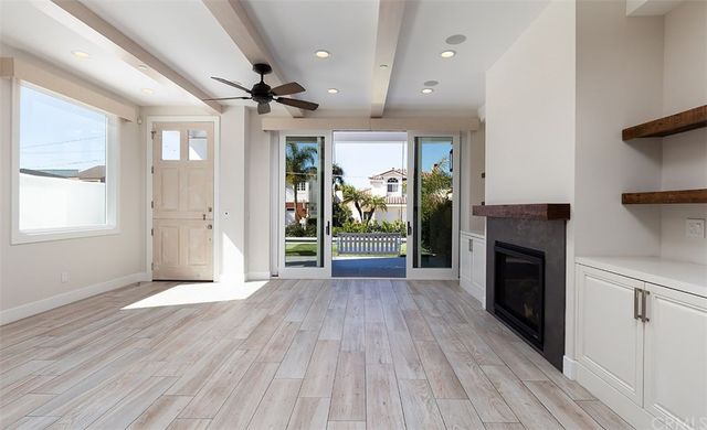 an empty room with wooden floor fireplace and windows