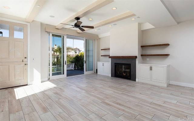 a view of an empty room with wooden floor fireplace and a window