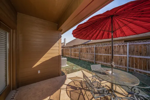 a patio with a table and chairs under an umbrella