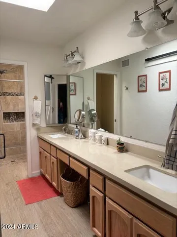 a bathroom with a granite countertop double vanity sink a mirror and shower