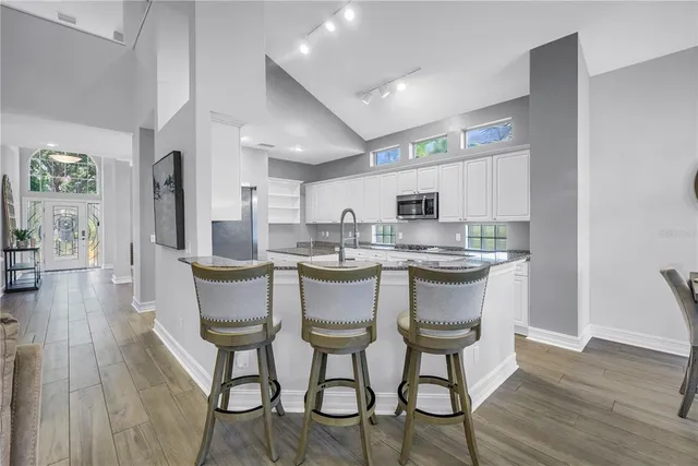 a kitchen with stainless steel appliances a dining table chairs and wooden floor