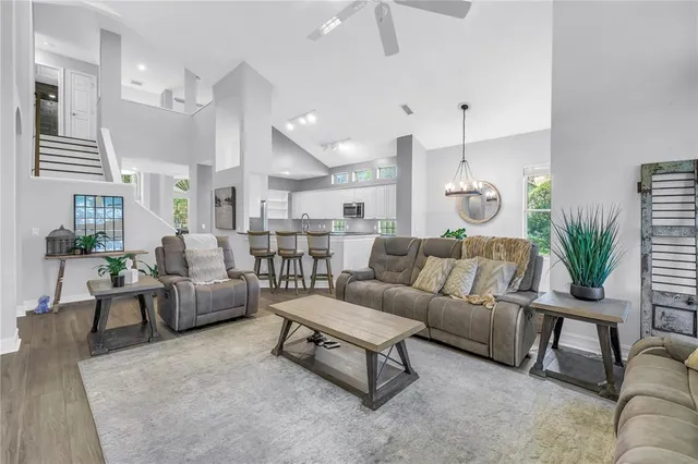 a living room with furniture kitchen view and a chandelier