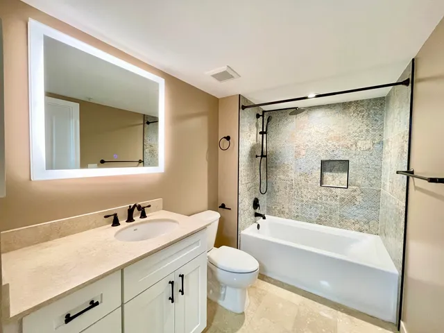 a bathroom with a granite countertop sink toilet and shower