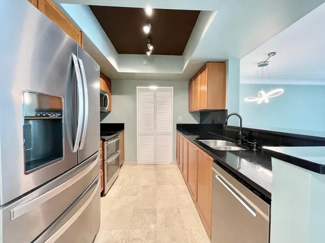 a large kitchen with stainless steel appliances a large counter top a stove and a refrigerator